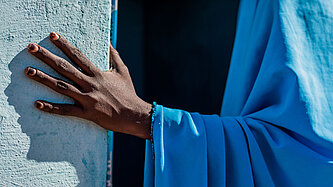 Eine Hand hält sich in einem Türrahmen fest.