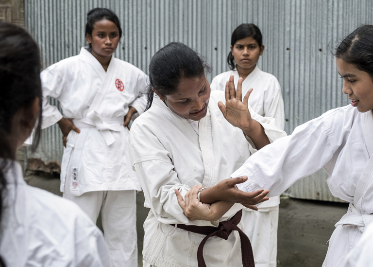 Eine Frau zeigt einem Mädchen einen Karategriff