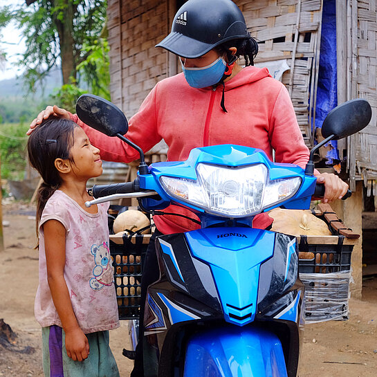 Mädchen steht neben ihrer Mama auf einem Motorrad.