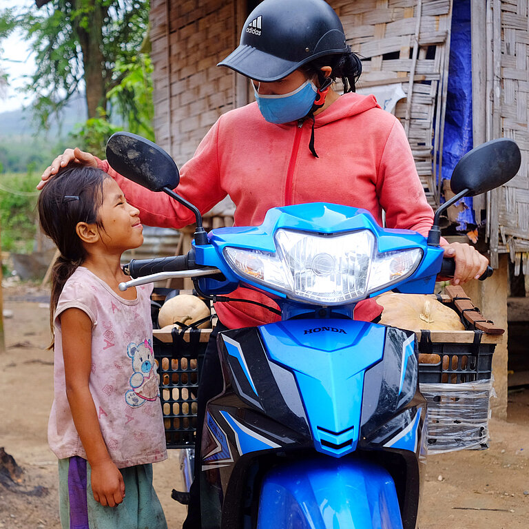 Mädchen steht neben ihrer Mama auf einem Motorrad.