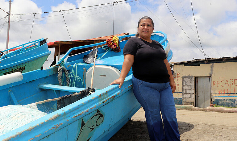 Eine Frau steht an ein Boot gelehnt, das am Strand steht