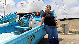 Eine Frau steht an ein Boot gelehnt, das am Strand steht