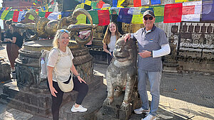 Familie Becker-Uebbing posiert vor einem Tempel mit Gebetsfahnen und steinerner Löwenstatue während ihrer Projektreise in Nepal.