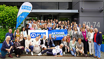Eine große Gruppe an Menschen steht vor dem Plan Bürogebäude in Hamburg. Sie halten einen Banner hoch mit dem Wort "Aktionsgruppen".