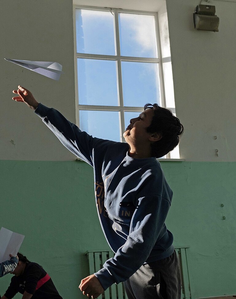 Ein Junge wirft Papierflieger