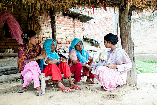Vier Frauen sitzen vor einem Haus und sprechen miteinander