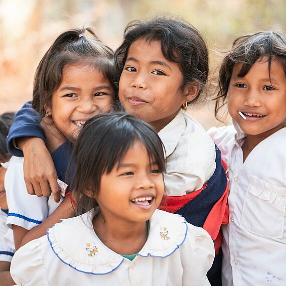 Fünf Mädchen lachen und umarmen sich
