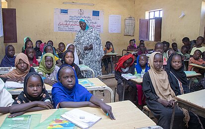 Kinder sitzen in einem Klassenraum an Schultischen