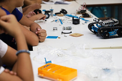 Ein kleiner Roboter sowie einzelne Bauteile liegen auf einem Tisch