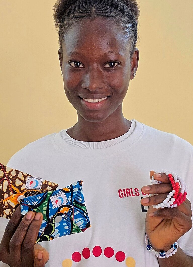 Carla steht bei einer Veranstaltung zum Menstruationsgesundheitstag und präsentiert Informationsmaterialien