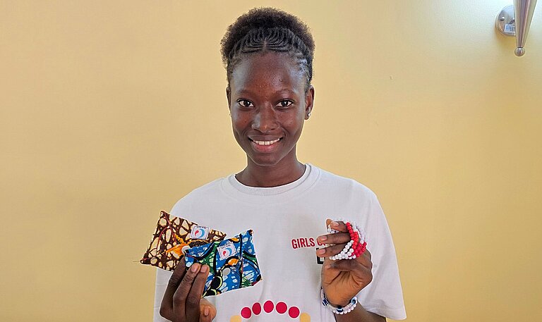 Carla steht bei einer Veranstaltung zum Menstruationsgesundheitstag und präsentiert Informationsmaterialien