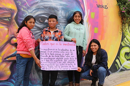 Vier Jugendliche halten ein selbstgeschriebenes Plakat