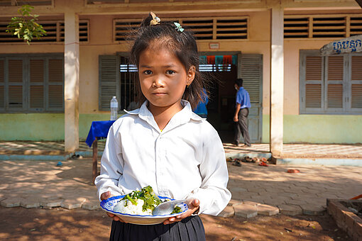 Kleines Kind mit einem Teller Reis und Gemüse