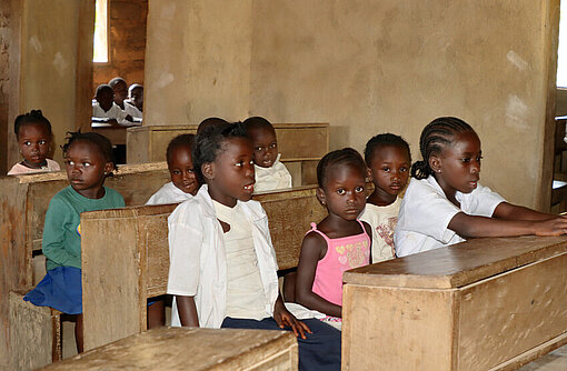 Schulmädchen in Liberia beteiligen sich am Unterricht, sitzen an Tischen und arbeiten gemeinsam im Klassenraum.