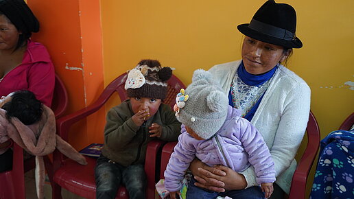 Eine Mutter und ihre zwei kleinen Kinder beim einer Schulung von Plan.