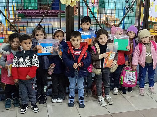 Einige der Kinder, die von Plan Schulutensilien erhalten zeigen ihre neuen Rucksäcke 