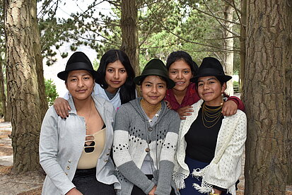 Fünf junge Frauen legen sich die Arme um die Schultern und lächeln