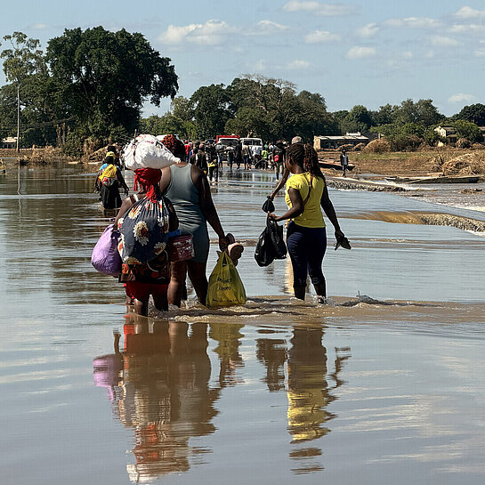 Mehrere Menschen waten durch Hochwasser in Mosambik