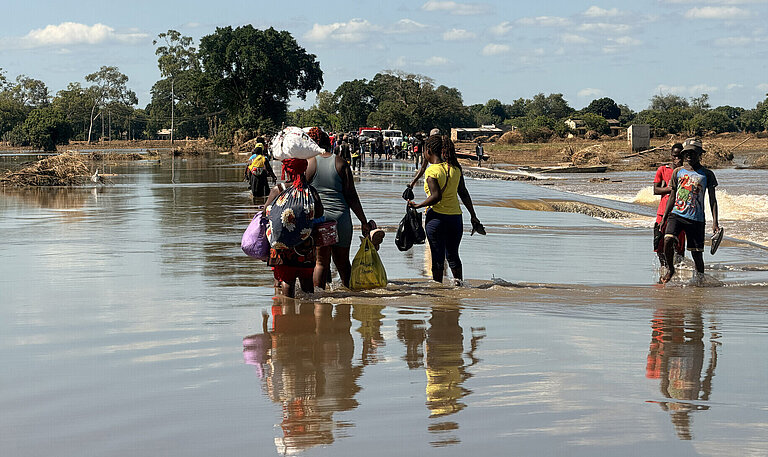 Mehrere Menschen waten durch Hochwasser in Mosambik
