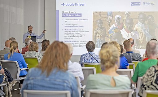 Ein junger Mann steht auf einem Podium und hält einen Vortrag