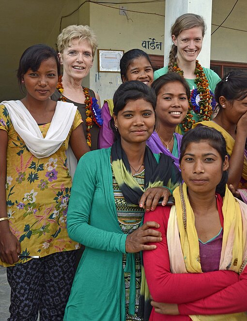 Nepalesinnen mit Saris stehen vor einem Haus in Nepal