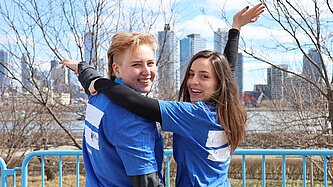 Zwei weiblich gelesene Personen tragen blaue T-Shirts, auf denen ein weißes Gleichzeichen gedruckt ist