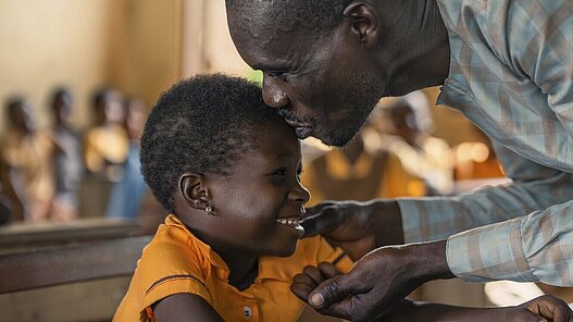 Michael, 41, gibt seiner Tochter im Klassenraum einen Kuss, wo er auch unterrichtet.