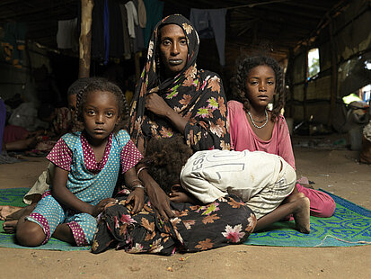 Geflüchtete Familie aus dem Sudan provisorischen Unterkunft, Nothilfe Geflüchtete Familie aus dem Sudan mit Mutter und Kindern, die in einer provisorischen Unterkunft sitzen.