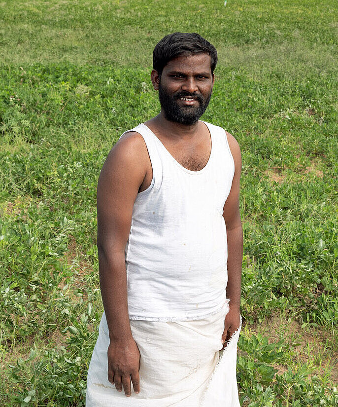 Ein Mann in Indien steht auf einem begrünten Feld