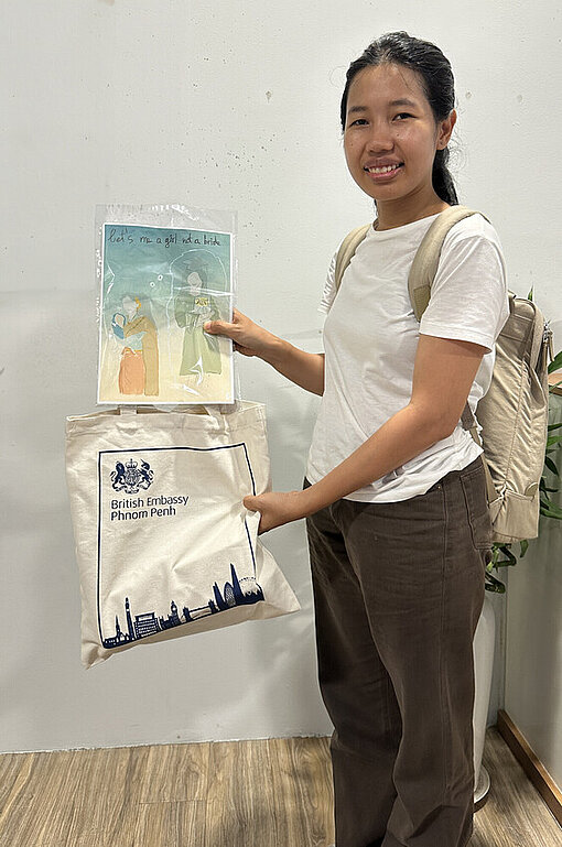 Eine junge kambodschanische Frau hält ein Kunstwerk in der Hand