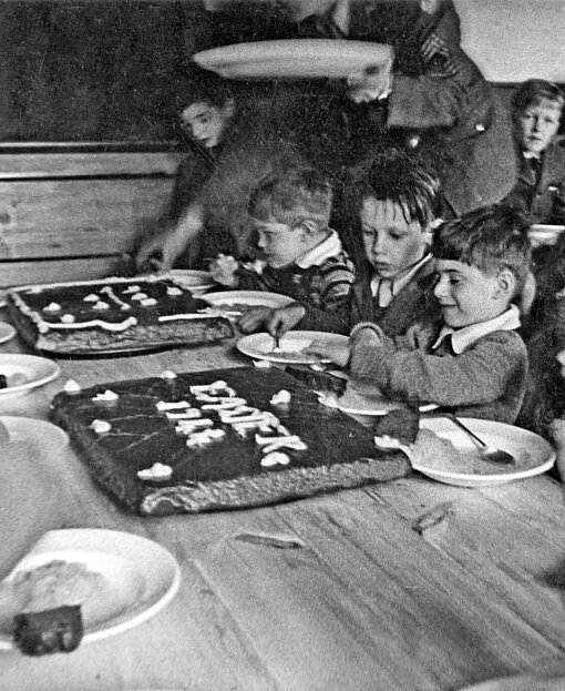 Kinder sitzen an einer Kuchentafel