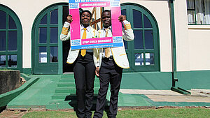 Zwei junge Aktivisten in Simbabwe setzen sich gegen Kinderehen ein und halten ein Plakat mit der Aufschrift 'Say No to Child Marriage
