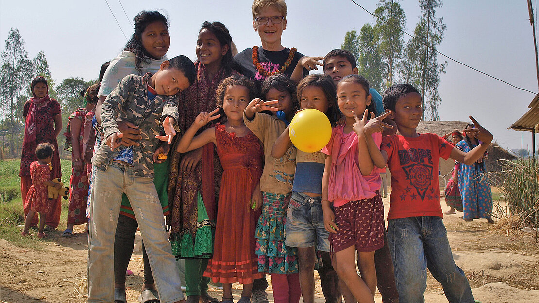 Henriette Kohland-Schönebeck umgeben von Kindern in ländlicher Umgebung in Nepal