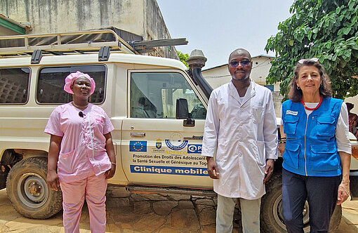 Drei Personen stehen vor einem weiß lackierten Geländewagen