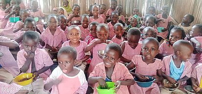 Viele Kinder sitzen am Boden und essen