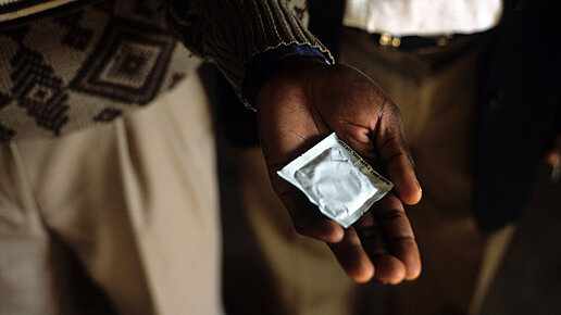 Eine Person hält ein Kondom in seiner ausgestreckten Hand