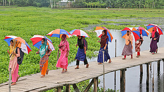 Frauen laufen auf einem Pfad durch Felder