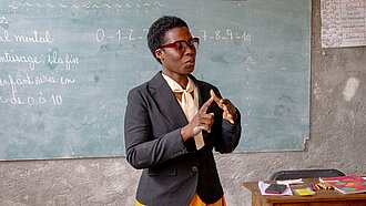 Eine Lehrerin erklärt das Zehn-Finger-Zählsystem