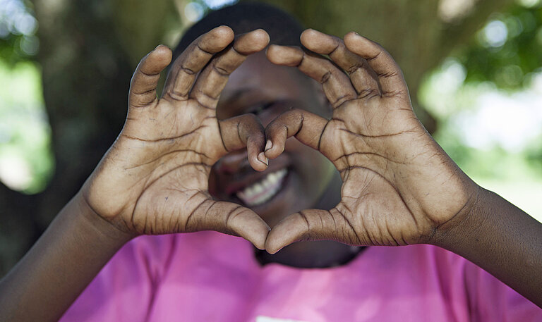 Ein Mädchen zeigt mit ihren Händen ein Herz