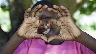 Ein Mädchen zeigt mit ihren Händen ein Herz