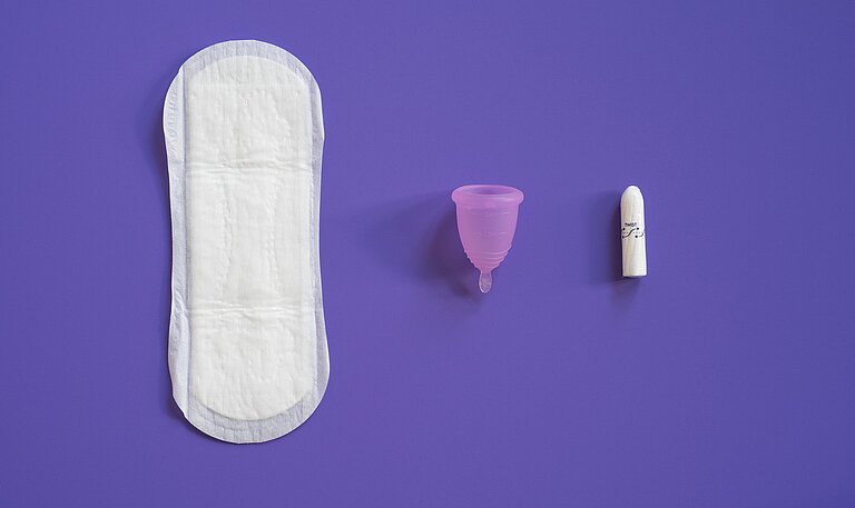 Eine Binde, eine Menstruationstasse und ein Tampon liegen lebeneinander
