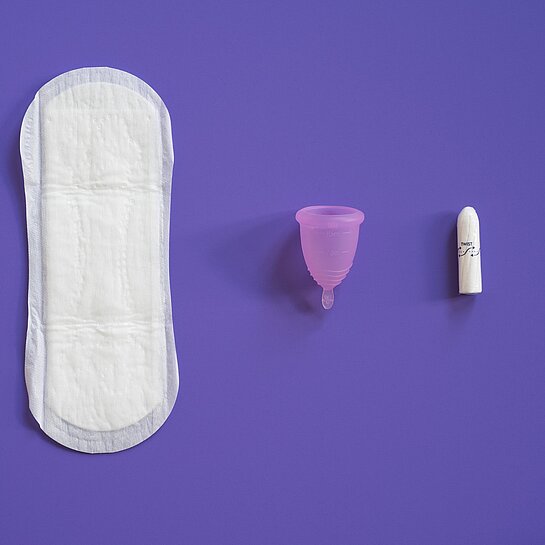 Eine Binde, eine Menstruationstasse und ein Tampon liegen lebeneinander