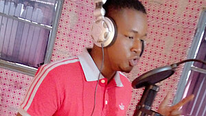 Junger Musiker bei einer Rap-Aufnahme im Tonstudio unger Mann mit Kopfhörern rappt in einem Tonstudio mit Mikrofon und Schallschutz