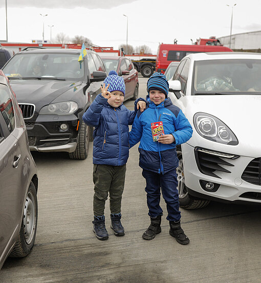 Zwei Jungen stehen zwischen parkenden Autos