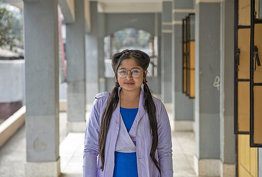 Eine junge Frau steht vor ihrer Oberschule