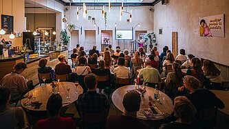 Etwa 50 Menschen sitzen in einem Raum zusammen