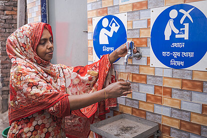 Eine Frau füllt ihr Glas an einer Trinkwasserstation