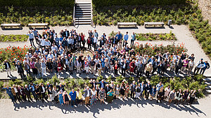 Gruppenfoto mit rund 120 Teilnehmer:innen des Stiftungstreffen, aus der Luft im Klostergarten aufgenommen.