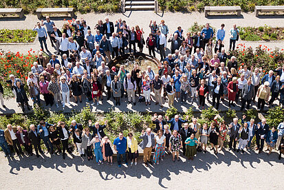Gruppenfoto mit rund 120 Teilnehmer:innen des Stiftungstreffen, aus der Luft im Klostergarten aufgenommen.
