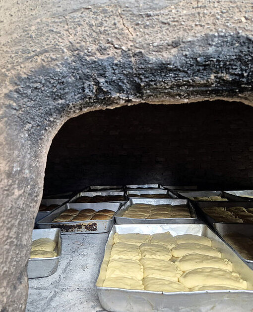 Empanadas werden im traditionellen Lehmofen gebacken Traditioneller Lehmofen mit einem Bleck Empanadas
